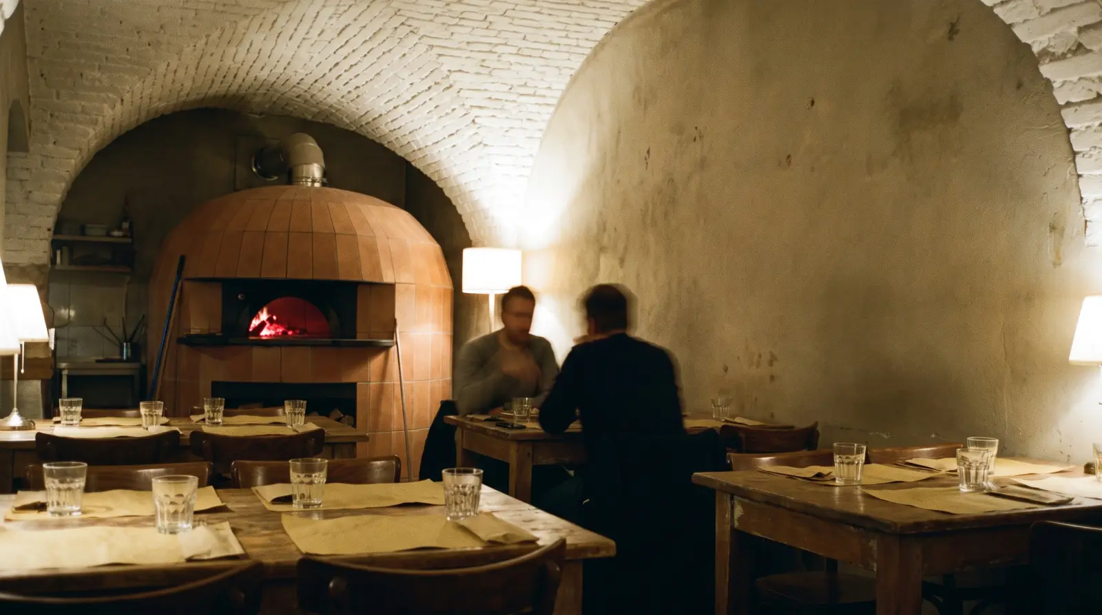 Sála pod bielou tehlovou klenbou, v pozadí horí pec